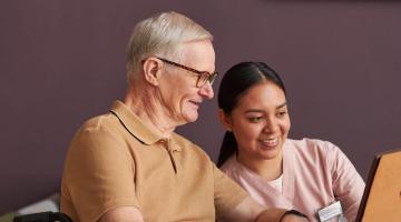 Woman using tablet computer with elderly man
