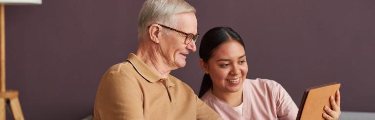 Woman using tablet computer with elderly man